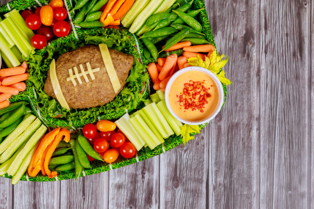 Football meatloaf with fresh vegetable platter and dipping for championship game fan party.